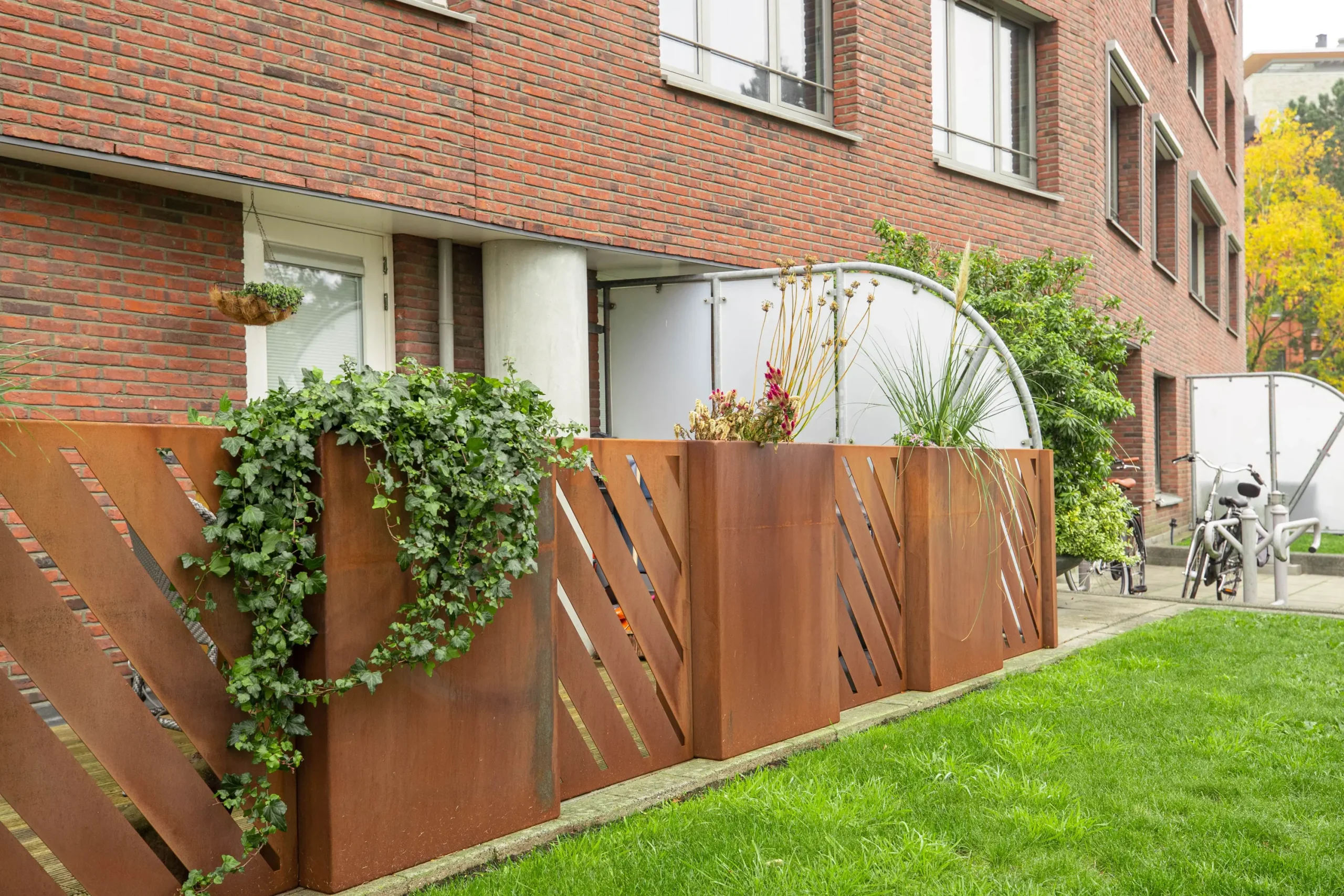 Plantenbakken en cortenstaal hekwerk bij appartementen
