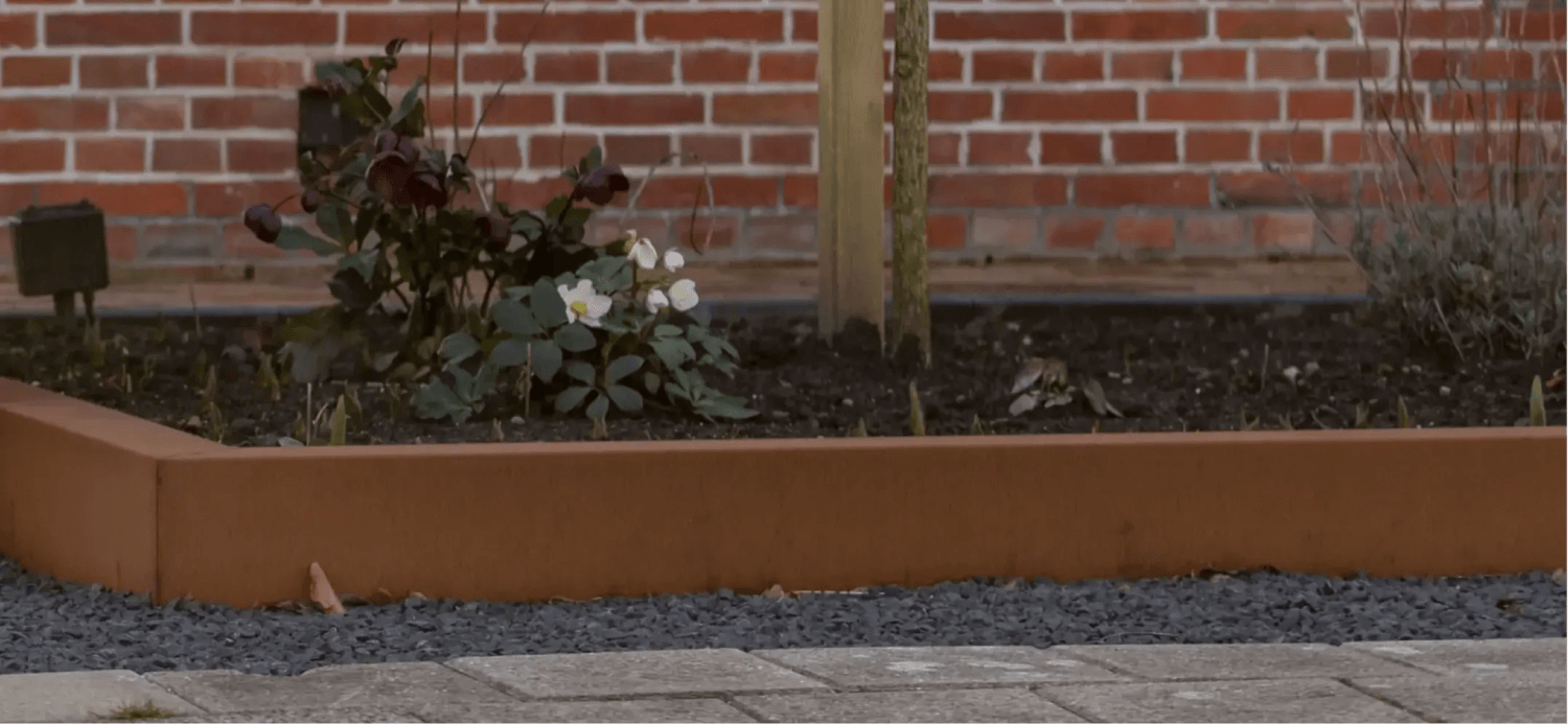 Cortenstaal tuinborder bij een bakstenen muur