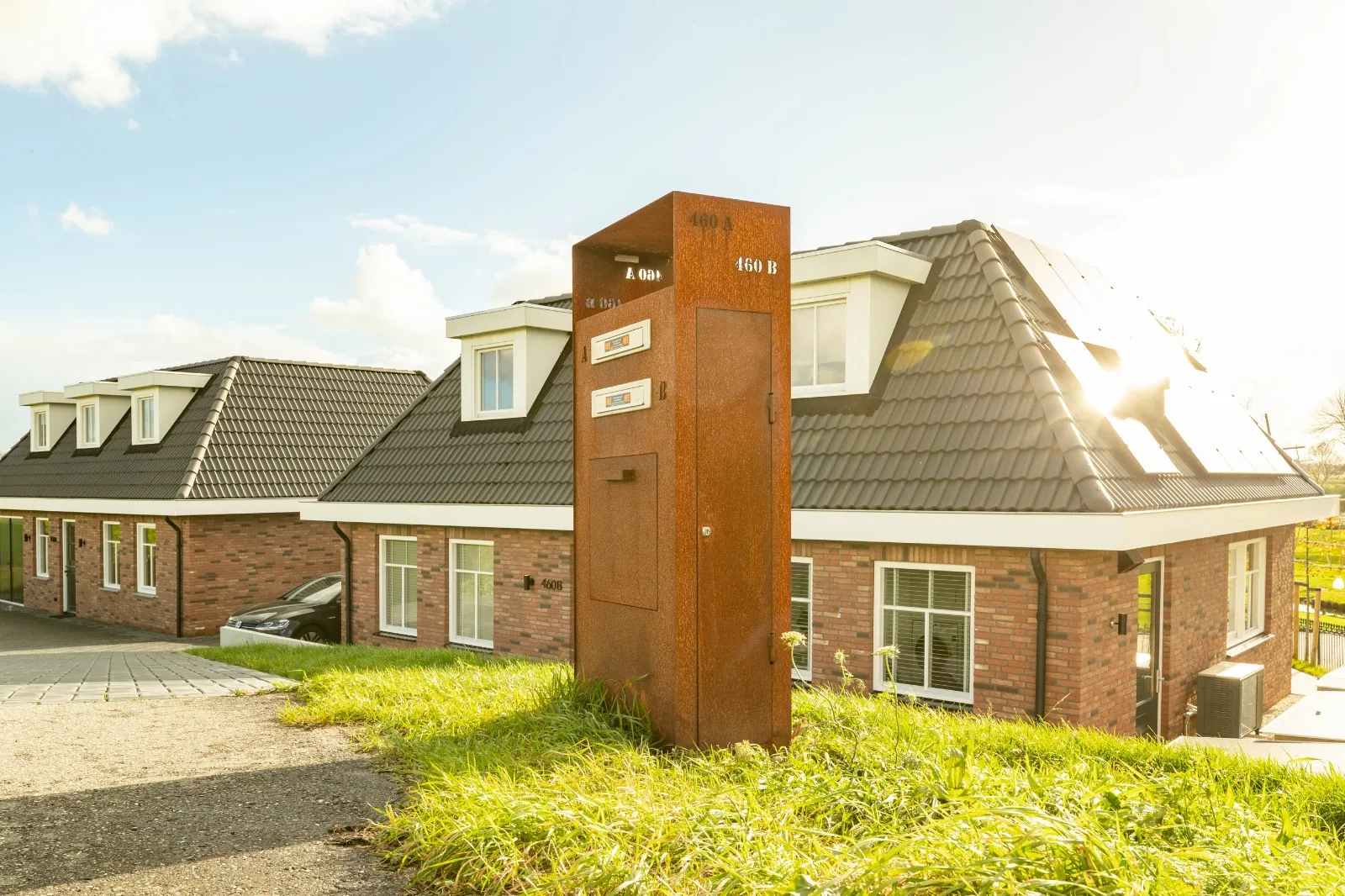 Brievenbuszuil van Staallokaal in het gras bij de oprit