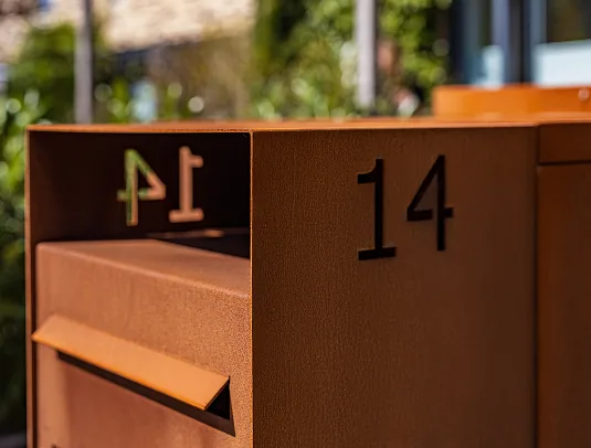 Hoekdetail van een stalen brievenbus met huisnummer 14