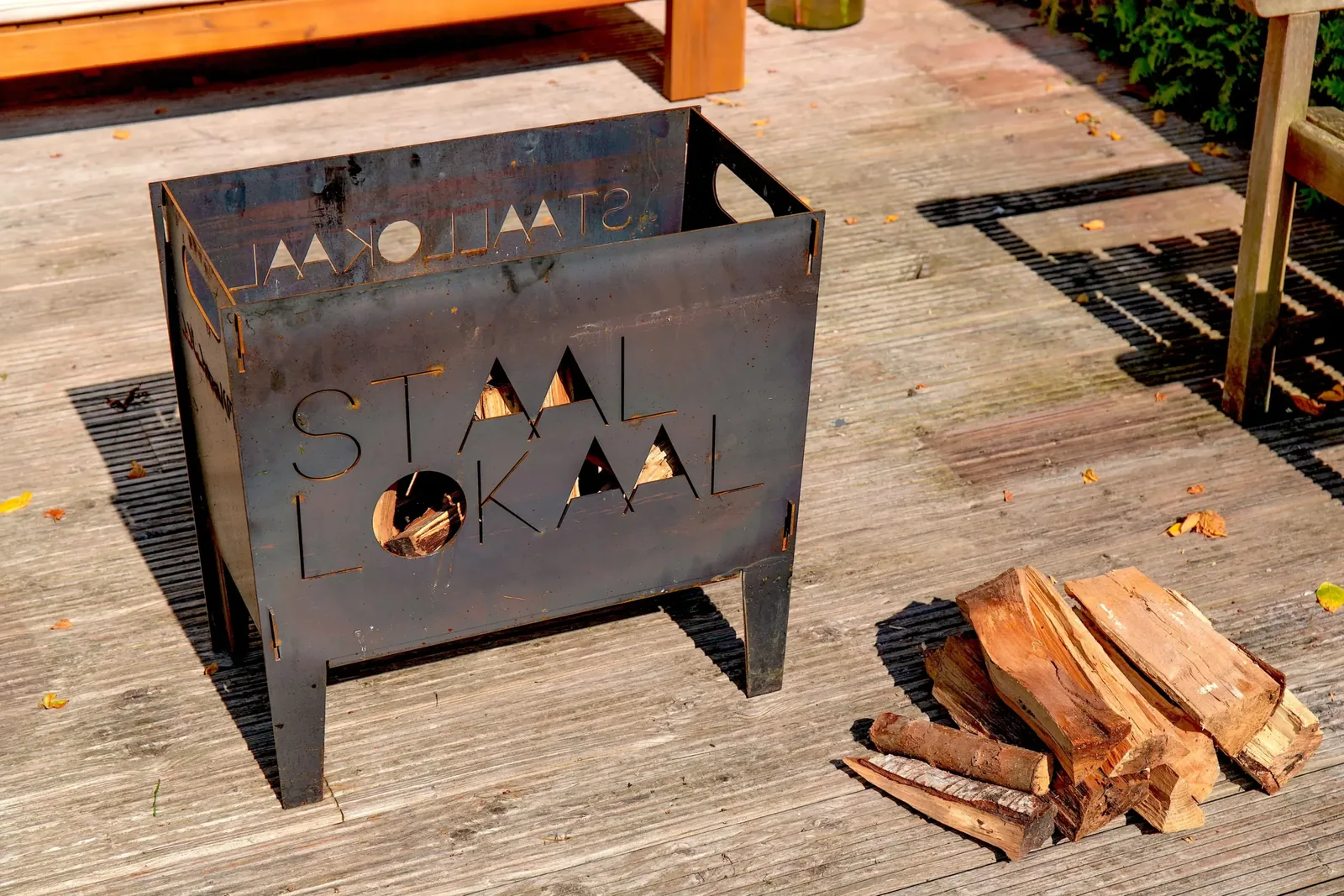 Cortenstalen vuurkorf op een terras naast een bord