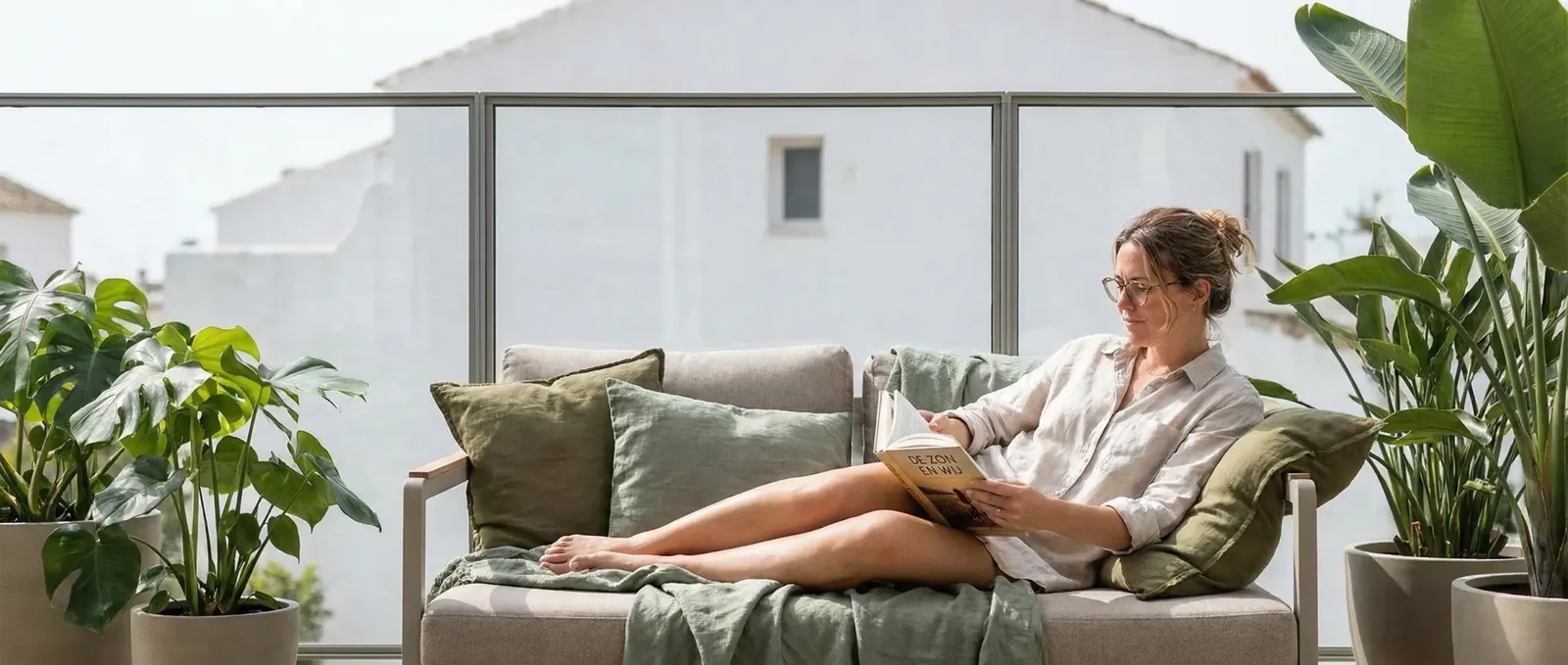 Vrouw leest op een terras achter het windscherm