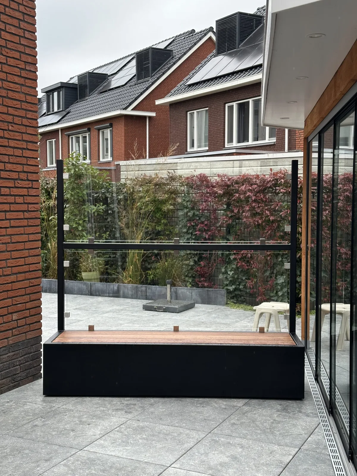 Glazen windscherm met zitbank op een terras