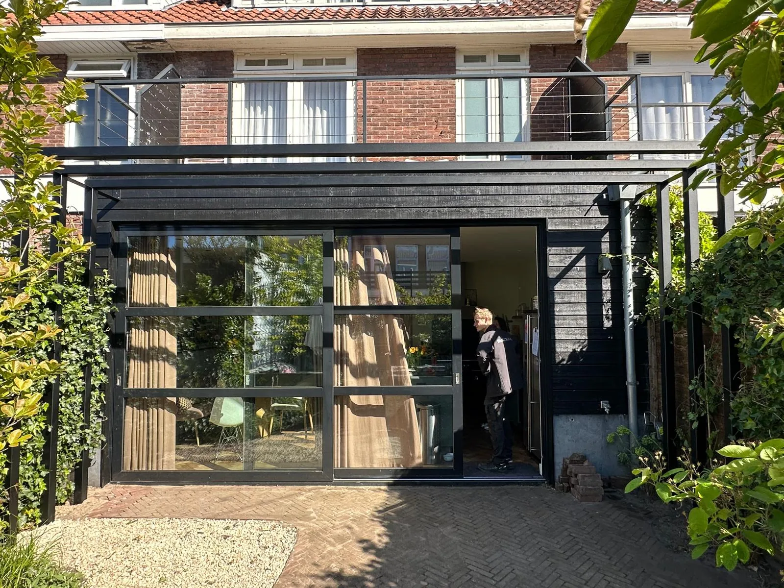 Zwarte stalen tuinkamer met glazen schuifpui