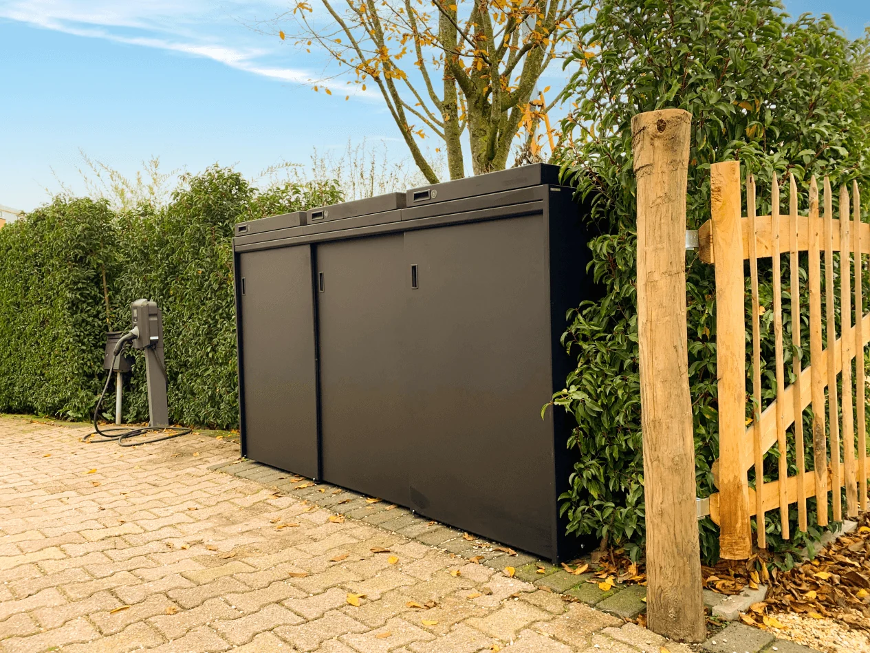 Zwarte containerombouw van Staallokaal langs de haag